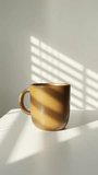 Morning mug of coffee sits on a table in the sunshine with shadow across the wall, interior calm  - Powered by Shutterstock - Get 15% off with code: PIKWIZARD15