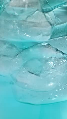 slow motion of ice cubes in cold blue cocktail drink. beverage closeup, macro