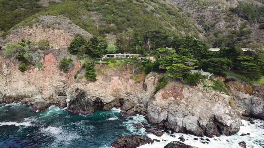 Drone shot of Mansion of the cliffs of the Pacific Ocean in Big Sur, California with breathtaking views of the forest near McWay Falls.