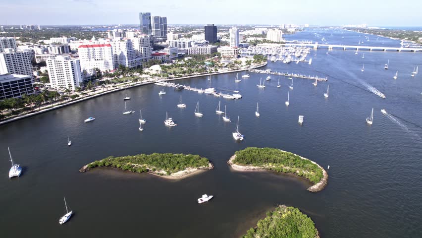 Push in tilt up drone shot of yachts, boats and West Palm Beach cityscape in Florida, USA