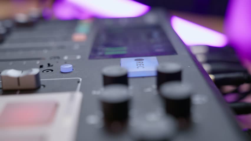 Hand pushes button to begin recording in audio booth or professional sound studio. Engineer clicking on REC button on audio console or mixer during live streaming show or radio session