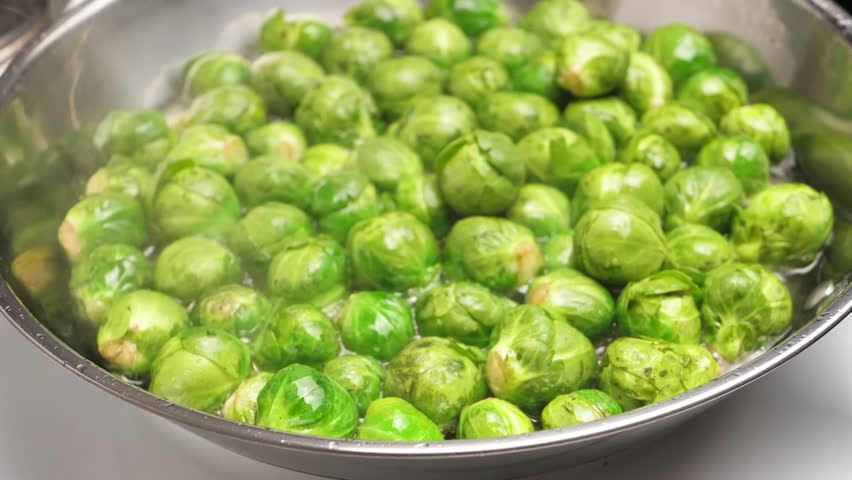 Top view of many green brussel sprouts boiling in hot vegetable oil inside a frying pan. Cooking fried sprouts of brussel sprouts fresh cabbage. Vegetarian food fried or boiled. Diet and vegetarianism