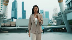 Portrait of young Asian woman entrepreneur talking on phone walking in modern city. Happy Thai female in formal pantsuit calls to business partner by cellphone. Lady consults via cellphone - Powered by Shutterstock - Get 15% off with code: PIKWIZARD15