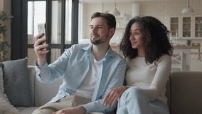 Young Smiling Interracial Couple Holding Smartphone, Making Video Call at Home - Powered by Shutterstock - Get 15% off with code: PIKWIZARD15