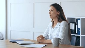 A focused woman sits at a wooden desk in her home office, using a laptop. Papers and a coffee mug are nearby as she engages in her work. - Powered by Shutterstock - Get 15% off with code: PIKWIZARD15