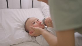 Asian young mother caring for and raising their baby boy at home. Attractive mom feeding baby from milk bottle, share tender moment as they nurture her little child in warm family environment in house - Powered by Shutterstock - Get 15% off with code: PIKWIZARD15