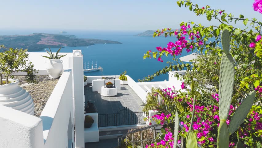 White architecture in Santorini island, Greece. Beautiful terrace with blooming pink flowers. Blue sea and the blue sky at sunny day. Travel and summer vacation concept. 
