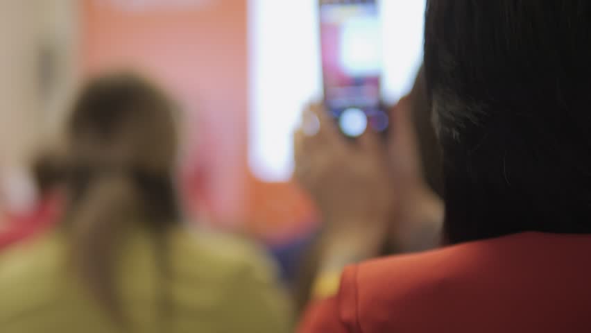 A woman is holding a cell phone and looking at it. Concept of modern technology and the way it has become an integral part of our daily lives