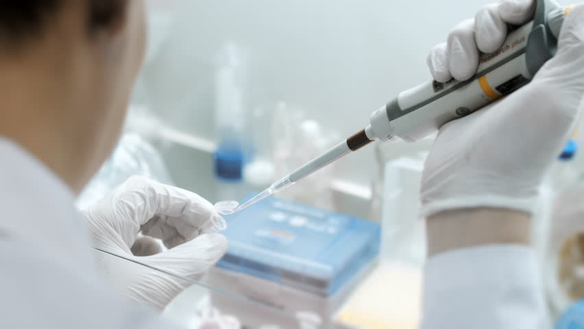 A genetics laboratory researcher drops samples with a pipette. Concept for studying DNA in a modern laboratory. Science and medicine. Lab Experimentation for Genetic Studies.