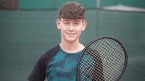 Portrait of a handsome teenage boy with red hair and blue eyes looking at the camera and smiling on a tennis court. Tennis player. - Powered by Shutterstock - Get 15% off with code: PIKWIZARD15
