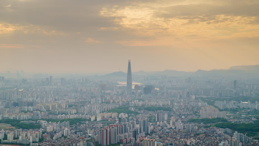 Stunning day to night time lapse of iconic view of Seoul, South Korea from Namhansanseong Mountain with Jamsil Tower prominently in the center. The sunset fades and the city skyline lights up.