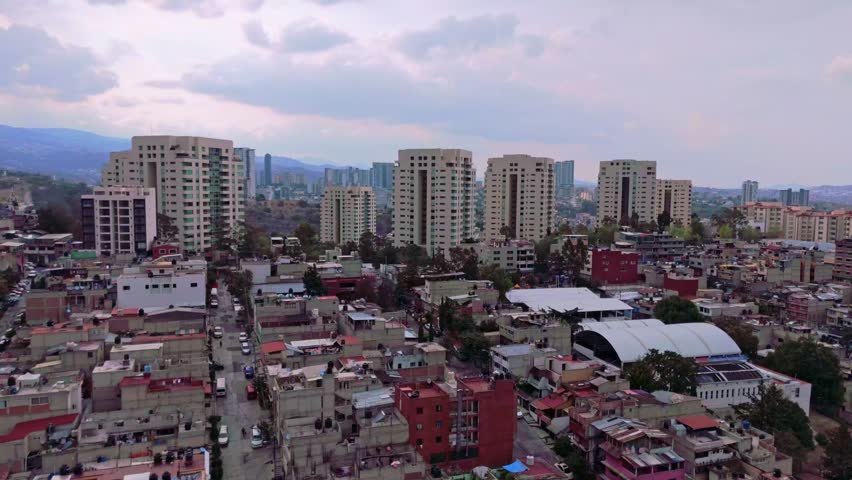 Aerial footage of Huixquilucan descends over densely packed homes, showcasing urban poverty, economic disparity, and social displacement amid Mexico’s urban development and gentrification issues.