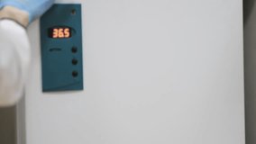 A scientist in a medical gown and protective gloves opens the refrigerator and takes out frozen samples. Modern national laboratory. DNA samples in the refrigerator. - Powered by Shutterstock - Get 15% off with code: PIKWIZARD15