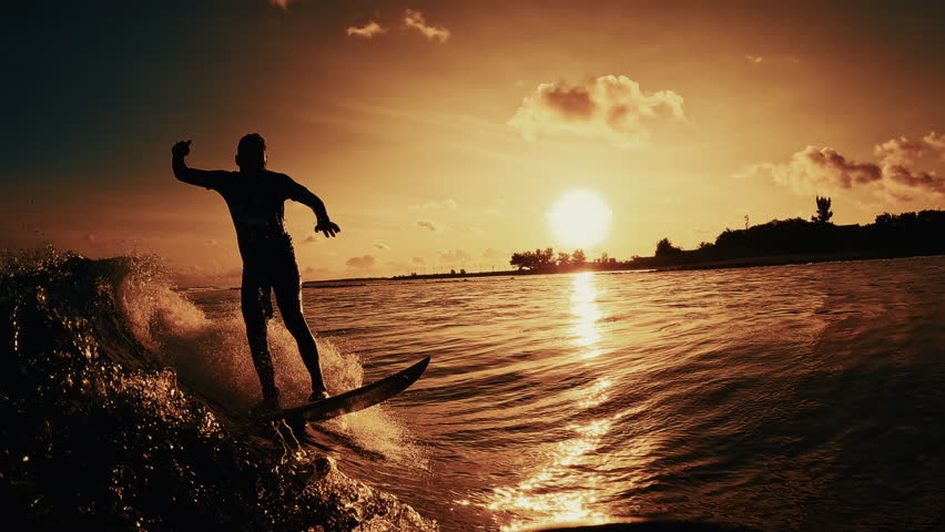 Surfer riding ocean wave at sunset including underwater view