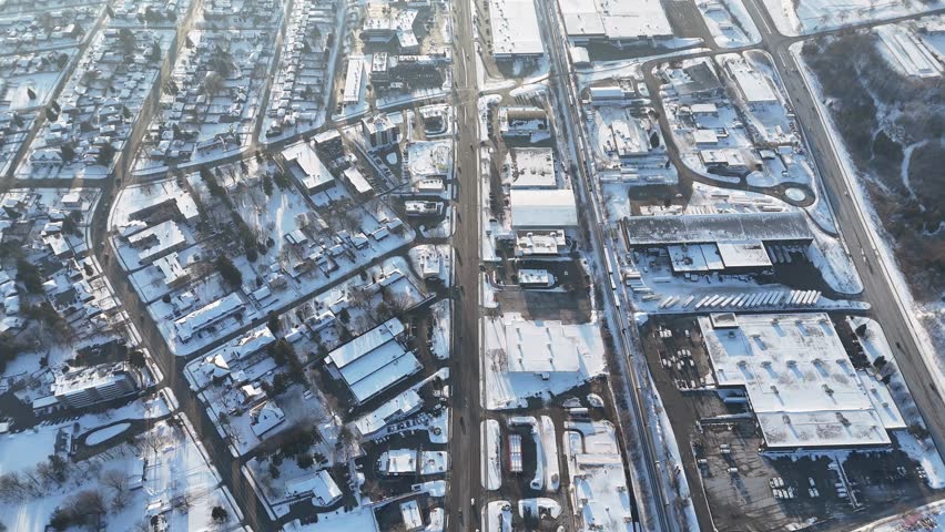 A drone footage over Snow-covered buildings and cars driving on streets in Waterloo, Ontario, Canada
