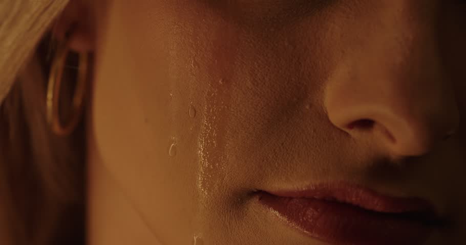 A tear flows down the cheek of a beautiful woman in slow motion, without eyes