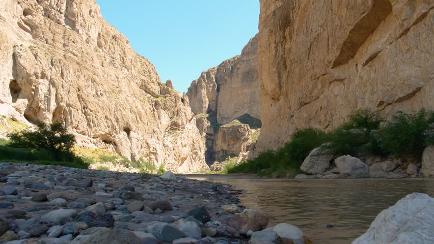 Big Bend National Park - Rio Grande in 4K: Slow zoom from the river’s surface shows flowing water, pebbles on the U.S. side, and towering rock mountains on Mexico