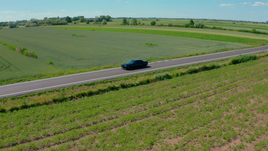 Sweeping drone orbit around a classic American muscle car A Black Dodge Chellenger 6.4l Scat Pack