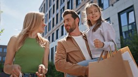Shopping parents daughter strolling on city street closeup. Smiling man woman with kid carrying grocery looking inside packages. Family of young wife husband couple walking together with child girl - Powered by Shutterstock - Get 15% off with code: PIKWIZARD15