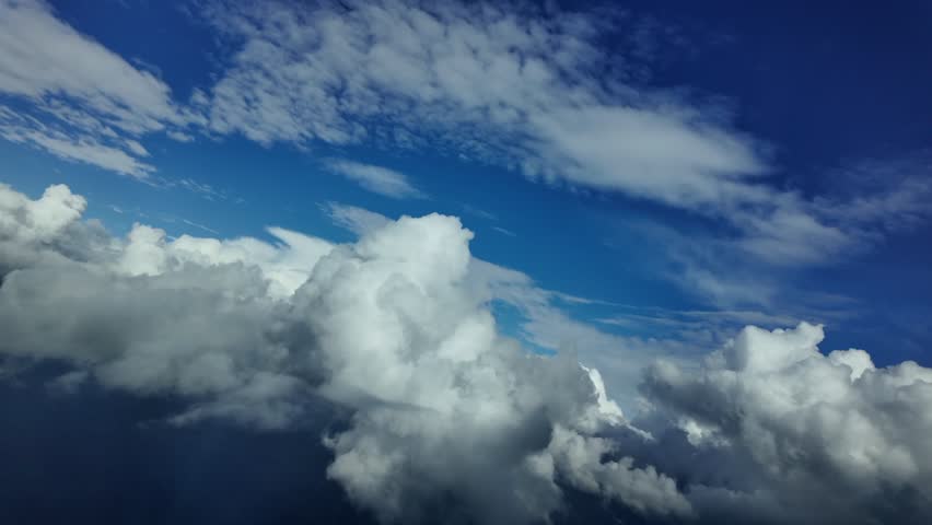 POV flying through white cottony cumulus clouds through the pilot’s eyes under a deep blue sky and over the Mediterranean Sea. 4K 60FPS