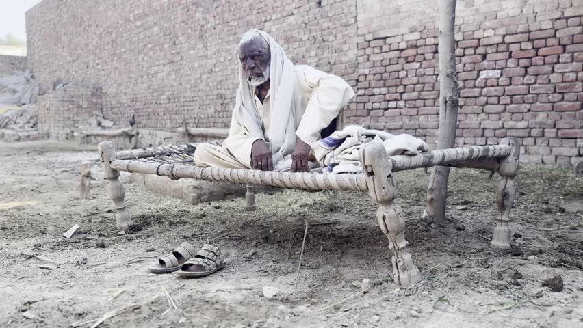An old, poor, and sick man sitting. His face is deeply lined, with wrinkles etched by years of hardship and exposure to the elements. His skin is weathered, tanned, or ashen, depending on his health.