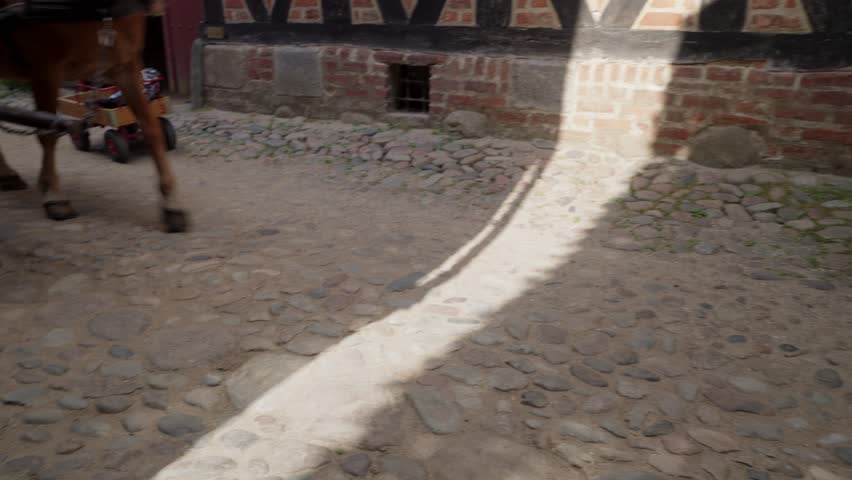 A view of a horse-drawn carriage wheel in motion at Den Gamle By in Aarhus, showcasing the craftsmanship and historical transport methods used in ancient Denmark.