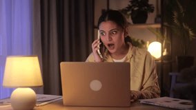 Young Indian woman working on a laptop in a cozy home office when she gets a phone call with exciting news. Her mood lifts instantly, and she celebrates with joy - Powered by Shutterstock - Get 15% off with code: PIKWIZARD15