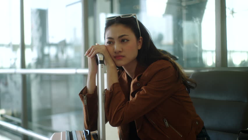 Unhappy young woman traveler disappointed with flight delay or cancelation while waiting at airport terminal, female tourist upset after receiving bad news when sitting at airline lounge.
