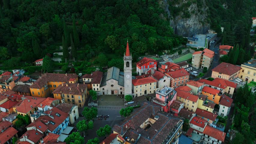 Aerial view of Lake Como in Italy during twilight, surrounded by majestic mountains and charming villages. The calm water reflects the sky and peaks, creating a stunning mirror effect. The picturesque