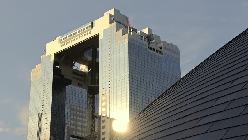 Umeda Sky Building in Osaka Japan and sunlight in evening. Landmark features a unique floating garden observatory connecting twin towers at top. Umeda Sky Building One of Osaka Landmark travel spot.