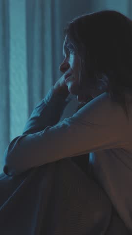 Unhappy depressed woman sitting in bed at night, she is nervous and suffering from insomnia