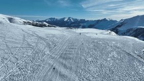 A vast snow-covered field dotted with ski tracks, with a couple of skiers exploring the expansive terrain. The clear blue sky and distant peaks create an idyllic winter sports destination - Powered by Shutterstock - Get 15% off with code: PIKWIZARD15