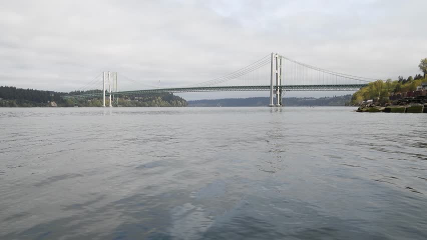 Tacoma Narrows Bridge linking Tacoma with Kitsap Peninsula from water level as Puget Sound moves in the foreground