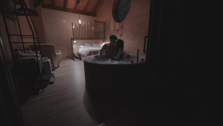 Passionate lovers sharing tender moments, closely embracing inside luxurious hydromassage tub, experiencing intimate connection within modern hotel room