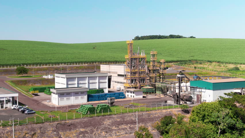 Aerial view of small refinery located in between a sugarcane plantation field during afternoon.