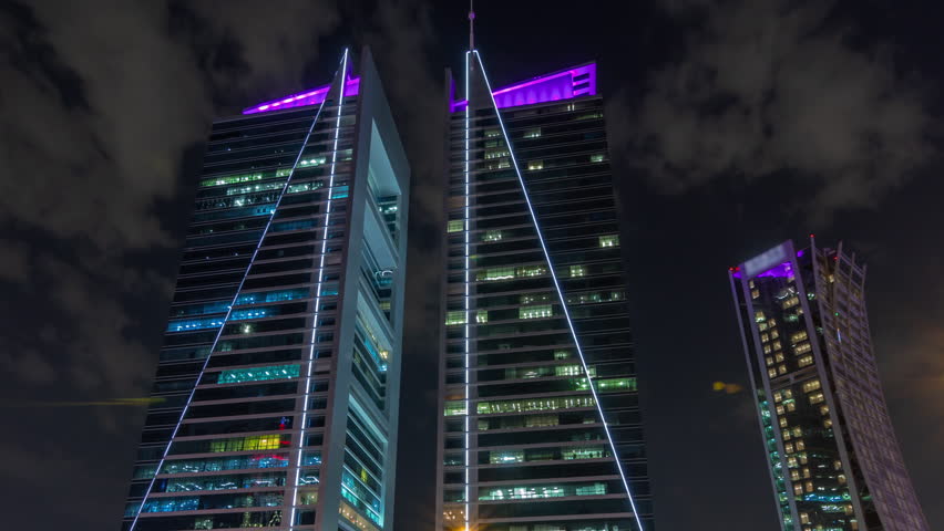 Modern skyscrapers on the Olaya street timelapse. Looking up perspective view to illuminated towers with glowing windows. Near shopping mall. Clouds on the dark sky. Riyadh, Saudi Arabia