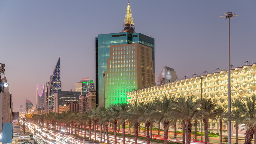 Aerial day to night timelapse of King Fahd Road in Riyadh, Saudi Arabia. Bustling traffic with cars and taxis near the illuminated Riyadh National Library, surrounded by modern towers and skyscrapers