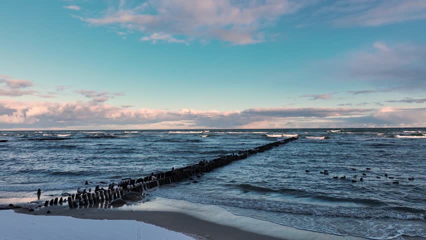 Calm Waves and Dramatic Clouds Over Serene Seascape During Late Afternoon Near Coastal Shore