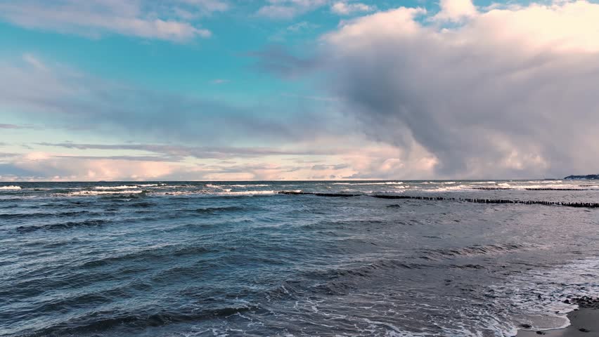 Calm Waves and Dramatic Clouds Over Serene Seascape During Late Afternoon Near Coastal Shore