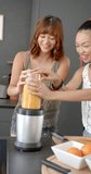 Vertical video: Making fresh juice, two women blending ingredients in kitchen together. Juicing, health, healthy lifestyle, teamwork, wellness, nutrition - Powered by Shutterstock - Get 15% off with code: PIKWIZARD15