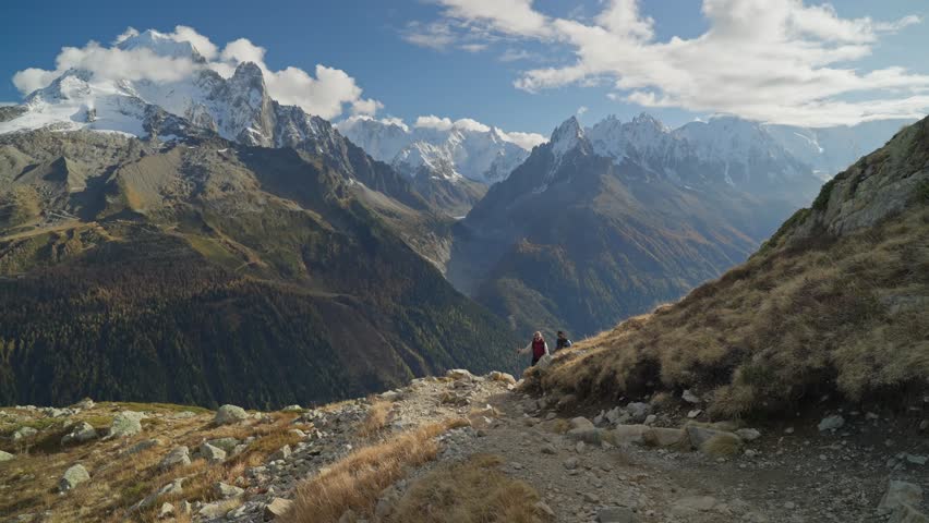 Hiking couple going up steep mountain terrain with Mont Blanc ridge in background