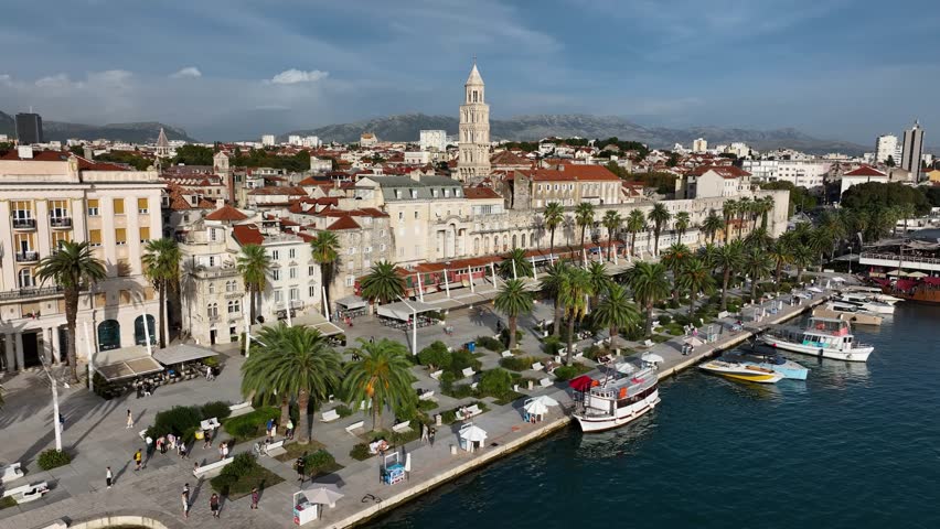 Drone shot of Split’s waterfront, Diocletian’s Palace, palm-lined promenade, and historic center, Croatia. Dolly in aerial