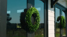 A close-up shot of a green wreath hanging on the front door of a wedding venue at a vineyard in South Georgia. The reflection of the vineyard and bright blue sky - Powered by Shutterstock - Get 15% off with code: PIKWIZARD15