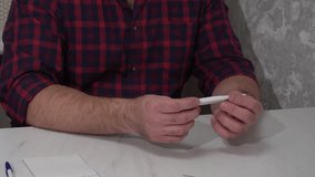 Man holding electronic thermometer and reading temperature at home - Powered by Shutterstock - Get 15% off with code: PIKWIZARD15