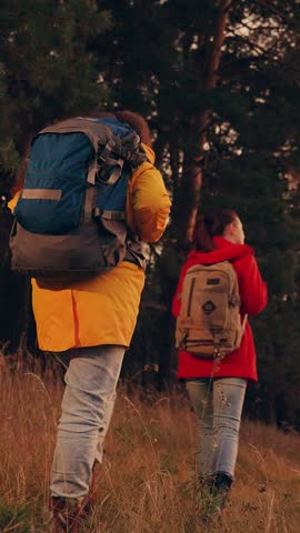 Women tourists with backpacks travel, walk in forest, sunset sky. Slow motion. Working in team of two Friends young women travelers, adventures on vacation. People with backpacks relaxing in nature