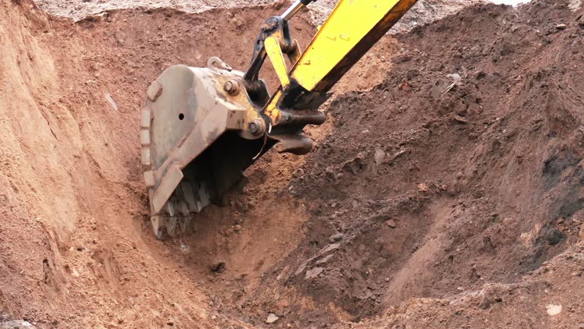 Excavator operates with precision, removing industrial debris while utilizing advanced AI earthmoving methods for an environmentally friendly demolition. Construction site shows extensive earthwork.