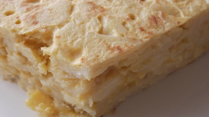 Spanish potato omelette with golden edges, sliced to reveal soft, fluffy interior