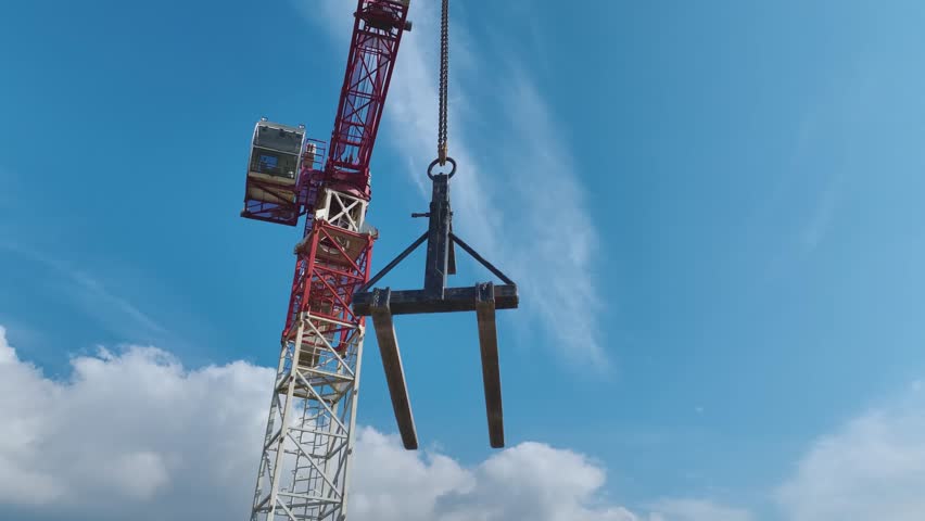 Aerial Video Aerial View of a Crane Lifting Heavy Materials Against a Cloudy Sky Backdrop