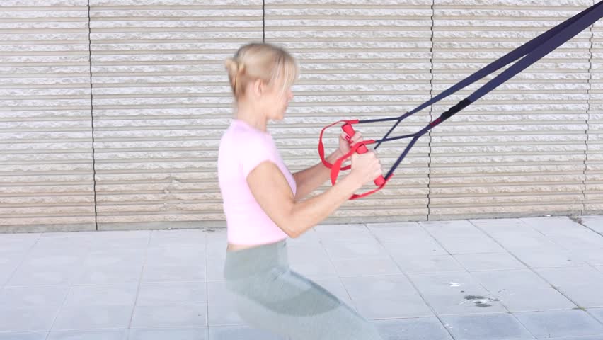 A woman in athletic wear demonstrates a suspension training exercise outdoors, showcasing a full range of motion and strength. Perfect for fitness, health, and training concepts