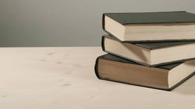 Stack of three vintage books resting on wooden table. The books are with dark covers. Minimalistic composition - slow sliding shot. 50 fps. - Powered by Shutterstock - Get 15% off with code: PIKWIZARD15